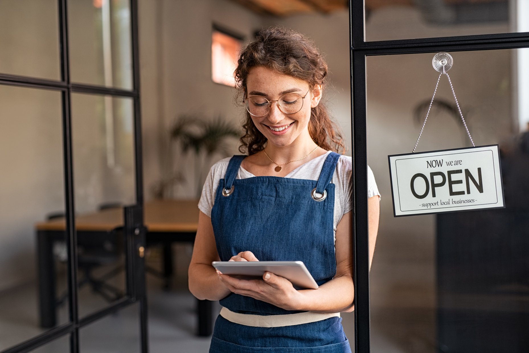 Small Business Owner Using Digital Tablet at Entrance